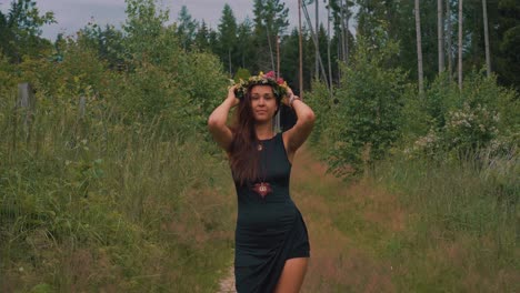 hippie femenina despreocupada poniéndose un tocado de flores en medio del bosque, cámara lenta