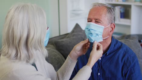 pareja caucásica de alto nivel usando máscaras faciales en casa