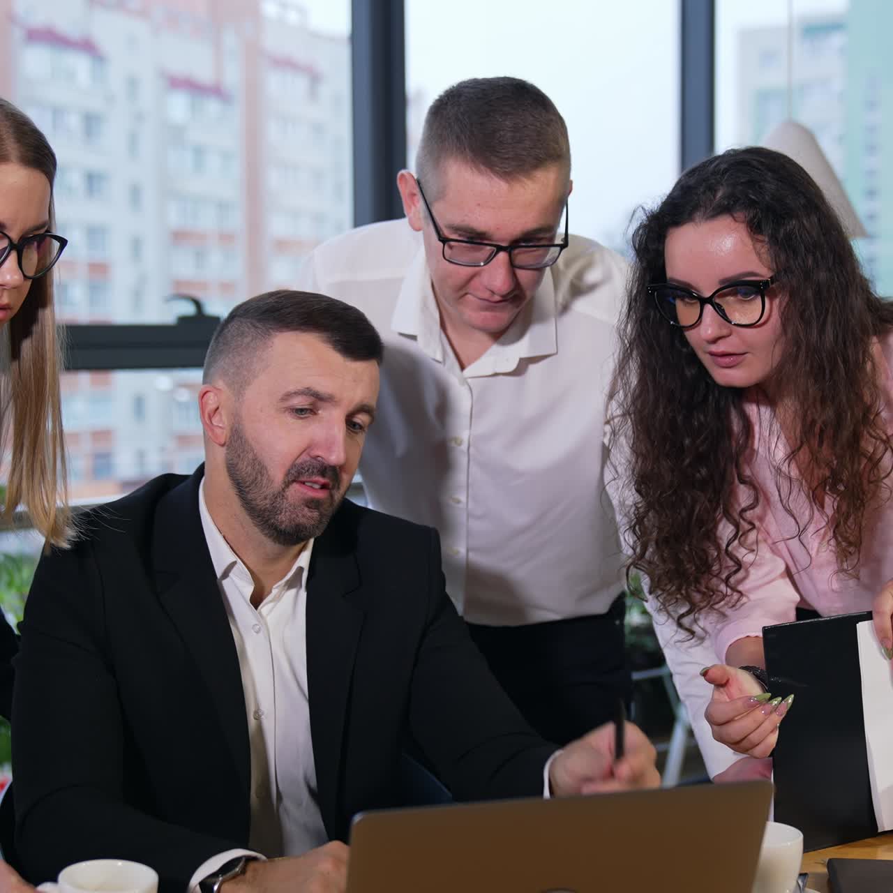 Co working of colleagues in the spacious office. All teammates gathered to look at laptop standing in front of boss