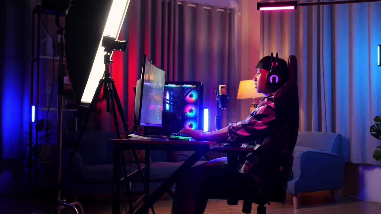 vista lateral del niño asiático streamer gritando gol celebrando el juego ganador a través de la red en la computadora personal. videojuego de transmisión en vivo, escritorio iluminado por luz de tira de led rgb