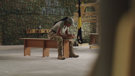 female soldier using smartphone in gym