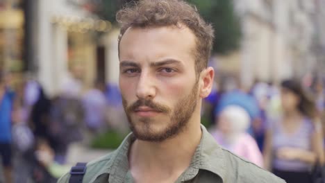 young man looking at camera in city street with crowd of people.