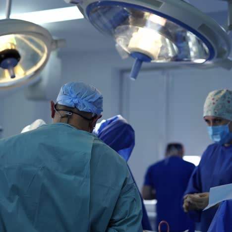 surgical team perform an operation. group of doctors in medical uniform conduct a surgery under medical lamps in clinic. saving lives