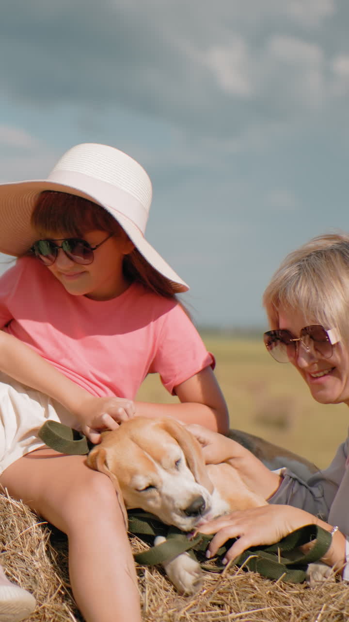 Una famiglia si diverte in una giornata di sole in una vasta campagna, con bambini che si arrampicano sul fieno, una donna che ride con gli occhiali da sole, colline ondulate e alberi sullo sfondo, erba dorata e un'atmosfera calda di campagna.