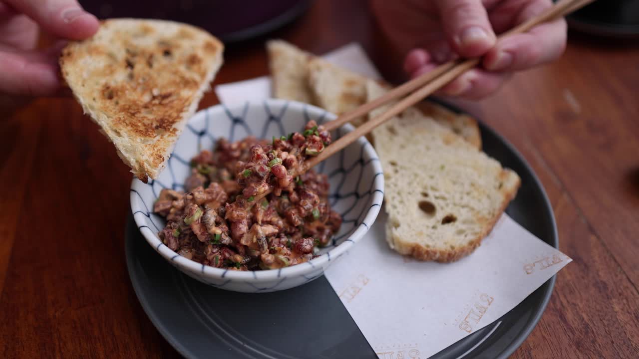 usando palillos para poner la comida en el pan