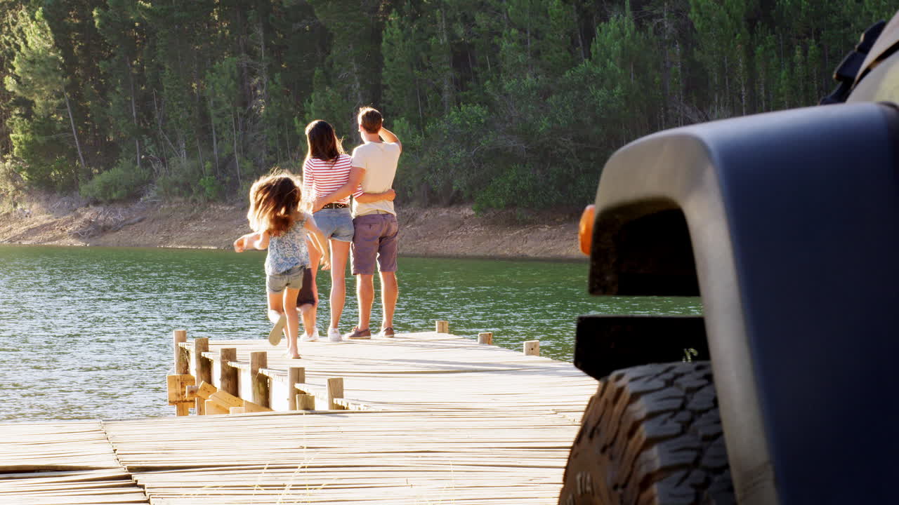 I bambini corrono per raggiungere i genitori che ammirano la vista sul lago su un pontile