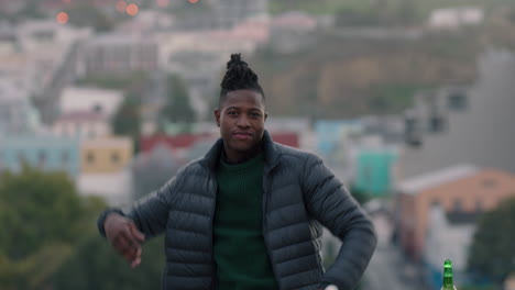 portrait young african american man on rooftop smiling confidently enjoying successful lifestyle in urban city at sunset
