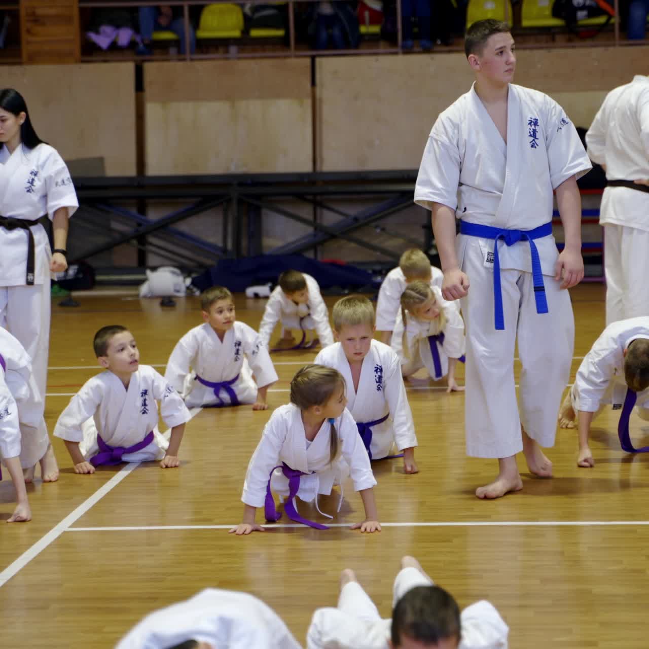 Boys and girls studying karate at the training in gym. Coaches walk and watch every young sportsman