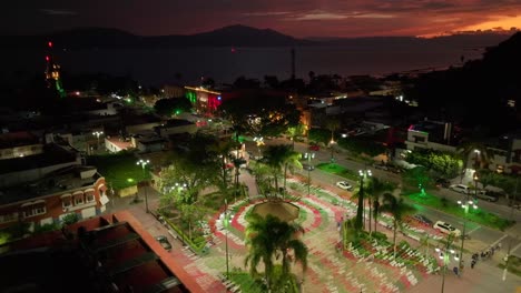 aerial view of a city at night with lake and mountains in the background