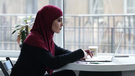 Attractive-young-muslim-girl-with-hijab-uses-laptop-to-find-some-important-information