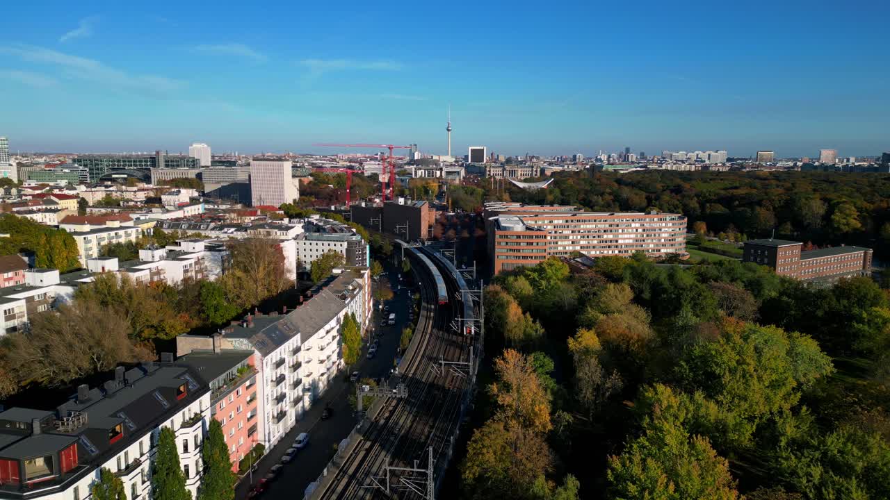 Scenic view of a train crossing a bridge over a river in berlin, surrounded by vibrant autumn foliage. Great aerial view flight speed ramp hyper motion time lapse