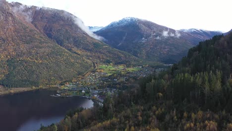 pueblo de kinsarvik revelado detrás de la ladera de otoño en un impresionante entorno paisajístico y majestuosas montañas - hardanger ullensvang noruega