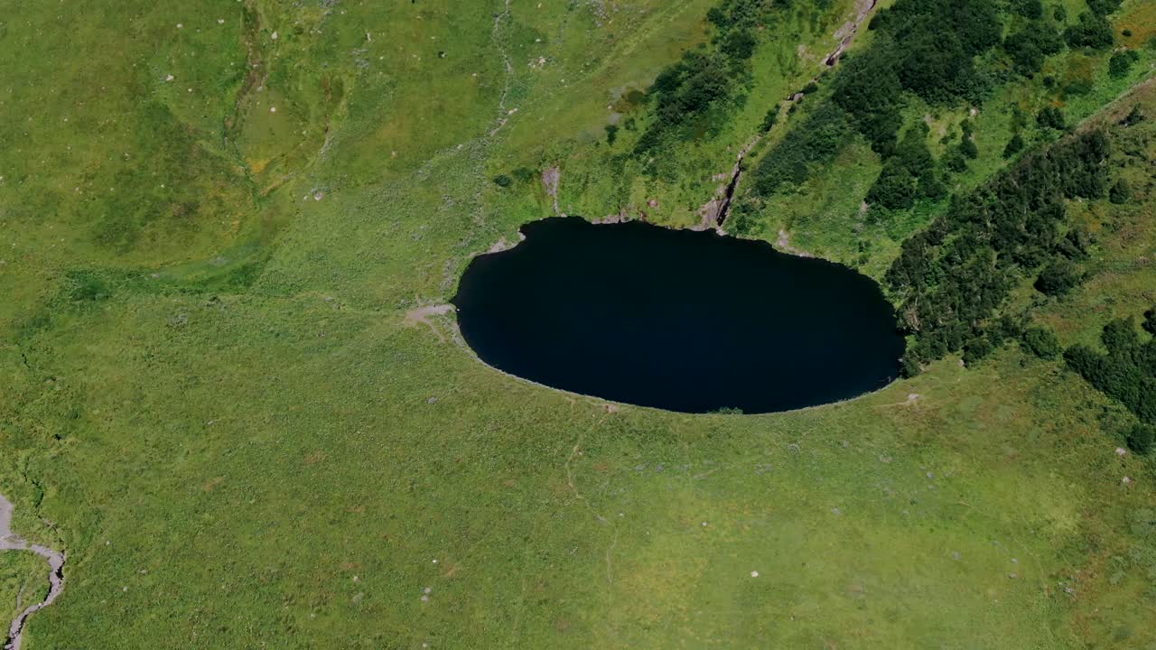 Utsikt fra den høye stien i Kaukasusfjellene, med isbreer, grønt gress og fjellsjøer.