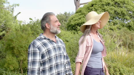 mature couple enjoying walk in lush green garden, smiling and relaxed