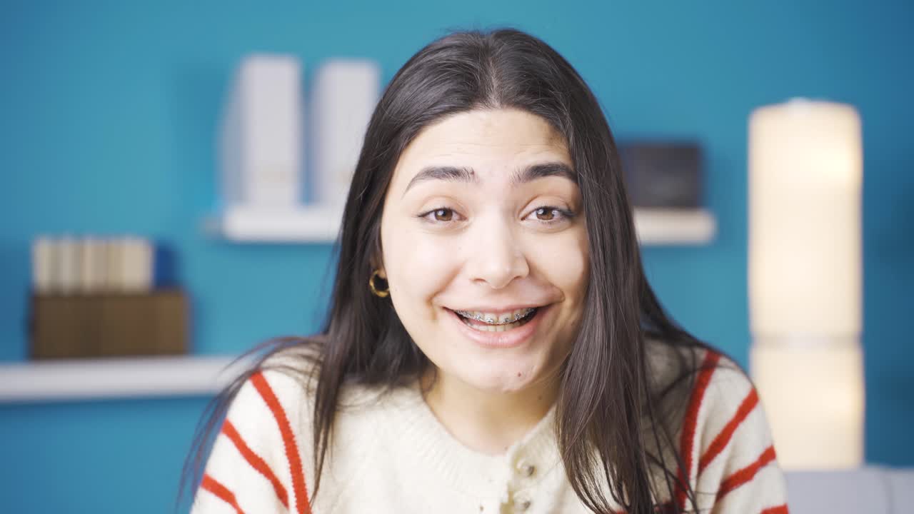 틀을 착용한 젊은 여성은 기쁜 소식에 놀랐고 기 ⁇ 합니다.