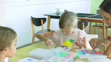 children learning beading crafts with a teacher