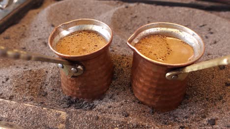 turkish coffee brewing in copper pots on sand