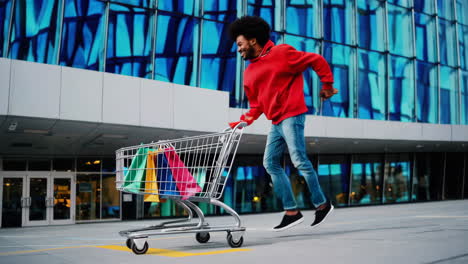 man running happily with a shopping cart full of colorful bags