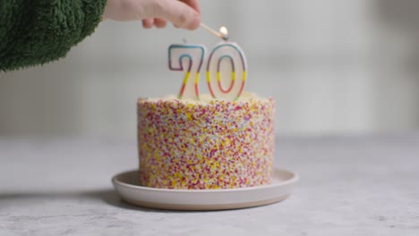 bolo de aniversário de foto de estúdio coberto com enfeites e vela comemorando o septuagésimo aniversário sendo aceso