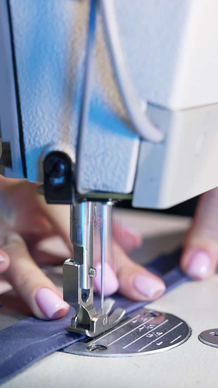 Female hands working on tailoring. Tailor working with sewing machine at fashion design workshop. Vertical video