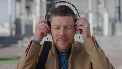 portrait young bearded businessman puts on headphones listening to music in city enjoying relaxed urban lifestyle caucasian male commuter