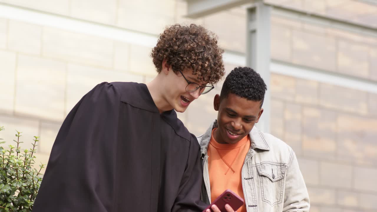 Amici di diverse etnie tirano fuori lo smartphone e scorrono i contenuti nel campus, mentre un laureato si sistema toga e tocco.