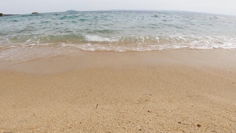 Eine-Nahaufnahme-Mit-Stabiler-Kamera-Von-Meereswellen,-Die-An-Einem-Sonnigen-Sommertag-Im-Mittelmeer-An-Einem-Sandstrand-Krachen