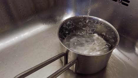 Fließendes-Wasser-Aus-Wasserhahn-In-Stahltopf,-Blasen-Auf-Der-Wasseroberfläche