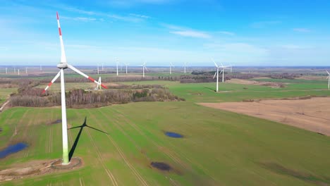 Aerial-footage-of-wind-turbines-in-a-wind-farm-generating-green-electric-energy-on-a-wide-green-field-on-a-sunny-day,-in-Taurage,-Lithuania