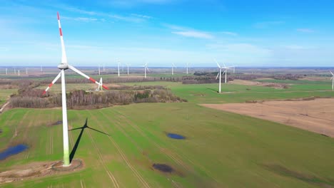 aerial footage of wind turbines in a wind farm generating green electric energy on a wide green field on a sunny day, in taurage, lithuania