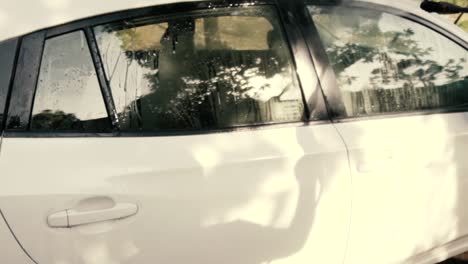 male cleaning a white car with a pressure washer