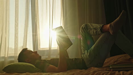 man relaxing and reading a book by the window
