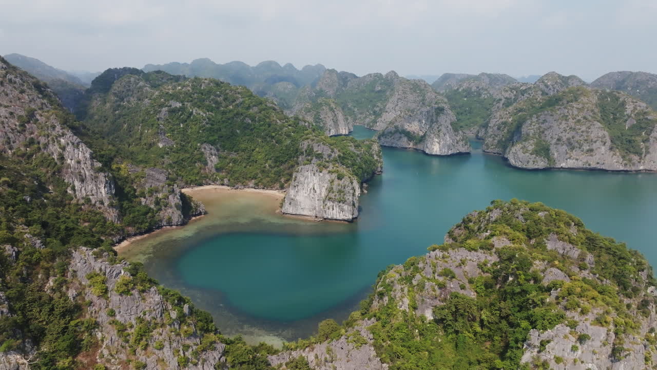 Cảnh quay drone Vịnh Cát Bà Việt Nam, với một vịnh mở giữa các hòn đảo đá vôi, những chiếc thuyền di chuyển trên làn nước xanh ngọc bích êm đềm.