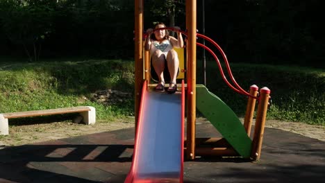 happy young woman sliding at children playground