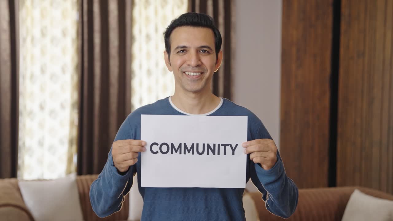 Happy Indian man holding COMMUNITY banner