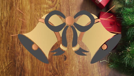 animation of christmas bells ringing over christmas decorations and gift boxes on table