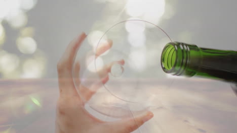 Composite-of-red-wine-being-poured-into-glass-held-by-woman-over-plant-background