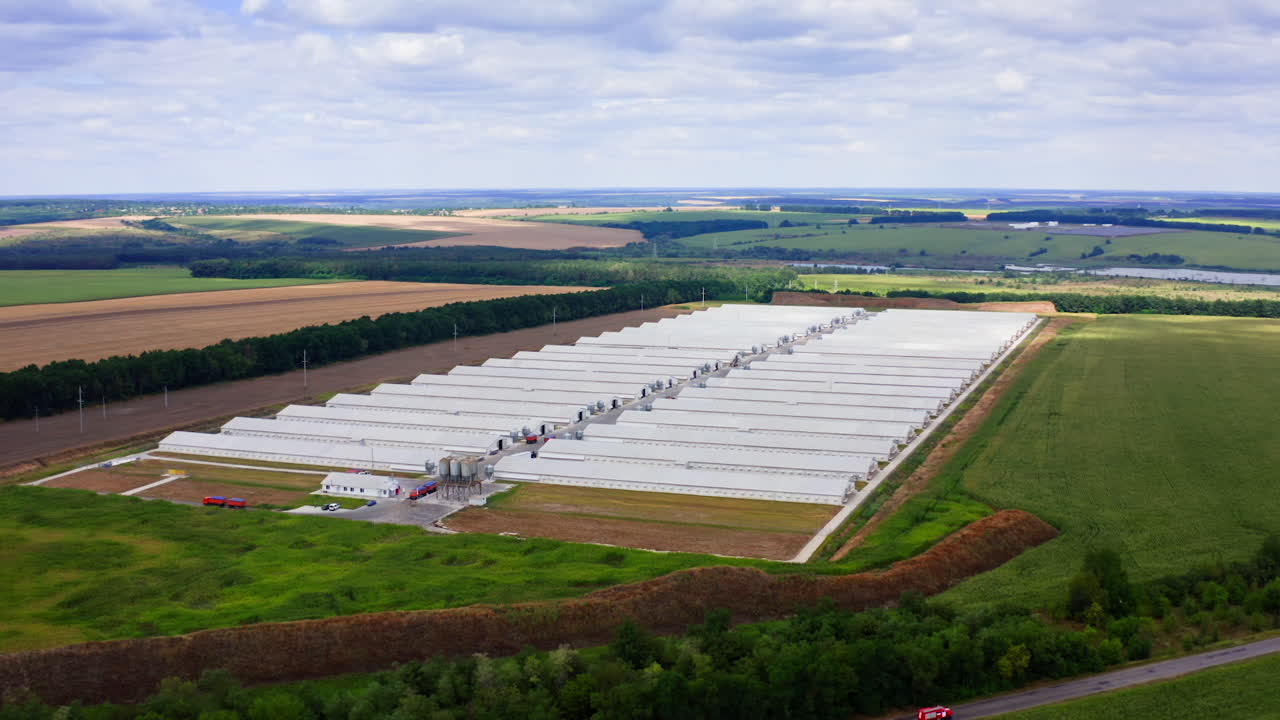 Modern farm poultry buildings. Newly built farm in green field. White roofs of long structures. Aerial view.