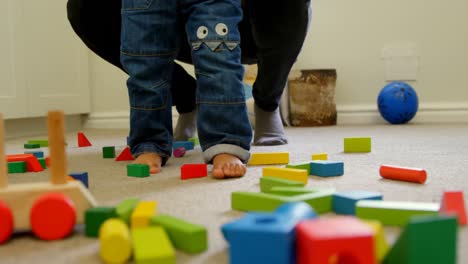 sección baja de un niño negro con su padre caminando sobre los bloques de construcción en una casa cómoda 4