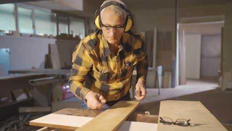 mide la madera. el carpintero mide la tabla con el medidor.
