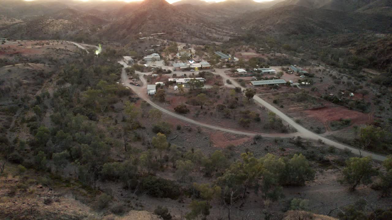Veduta aerea discendente del piccolo villaggio di Arkaroola al tramonto con la silhouette delle cime montuose