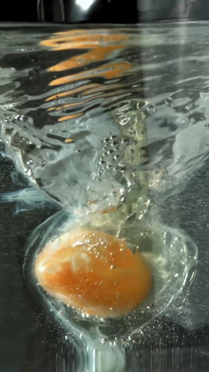 Raw Egg Yolk and White Falling into Water in Slow Motion