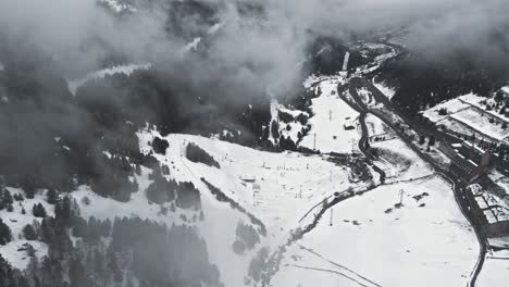 Aerial,-empty-ski-resort-in-a-gloomy-overcast-mountain-valley-during-pandemic