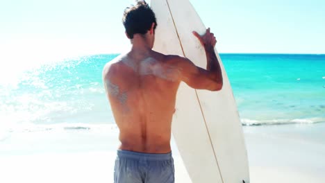 man standing on beach with surfboard
