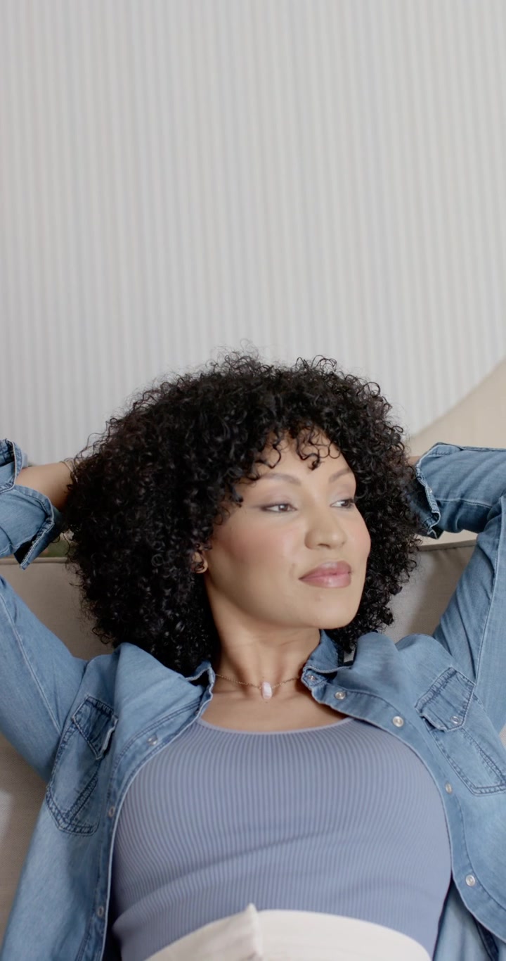 Video verticale: Donna adulta che guarda, appoggiandosi all'indietro sul divano con le mani dietro la testa cercando relax