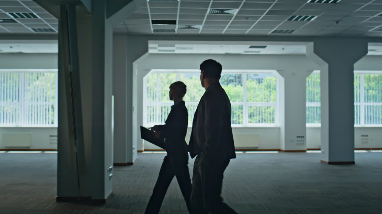 Businesspeople silhouettes crossing hall. Woman man discussing work together