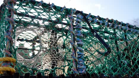 sunlight glare through stacked empty rope lobster crab baskets on waterfront harbour