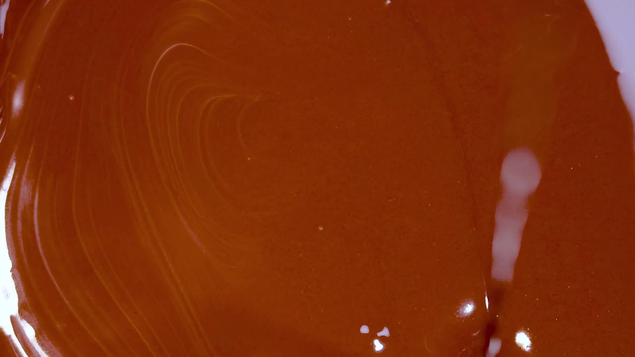 A detailed view of a smooth chocolate stream flowing and swirling in rich, glossy textures.