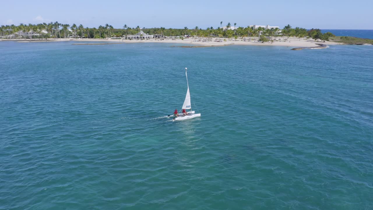 barco navegando en el caribe azul justo al lado de la playa bordeada de palmeras