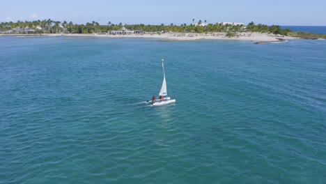 boat sailing in azure caribbean just off palm fringed beach